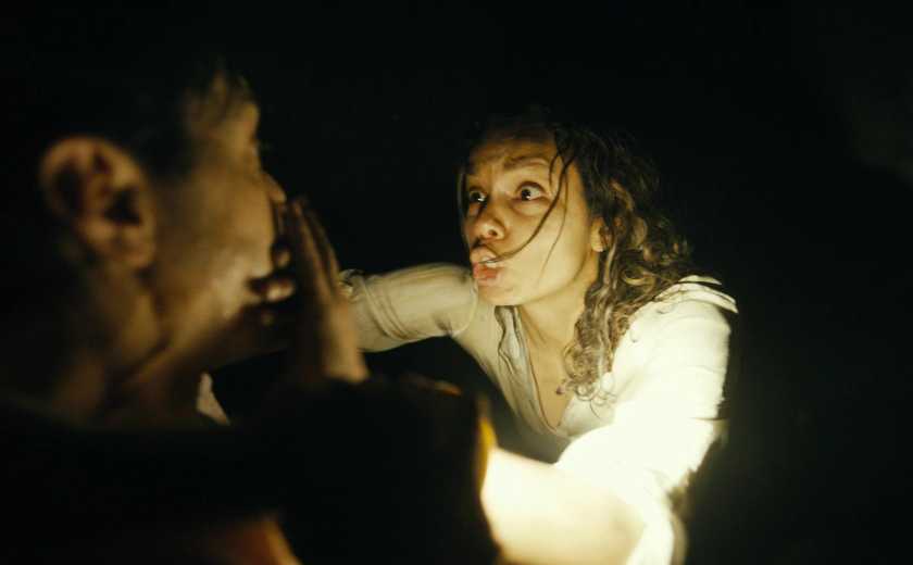 Georgina Campbell as Tess Marshall shushes Justin Long's AJ Gilbrand. They sit in a dark, dimly lit room.Image from Barbarian from 20th Century Studios.